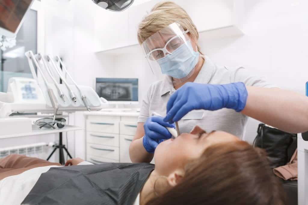 Dental Aerosol Fume Extractor in Use while Dentist Operating on a Patient